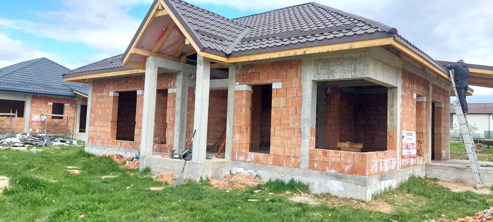 Casă la roșu cu acoperiș montat și coloane de beton, Maramureș