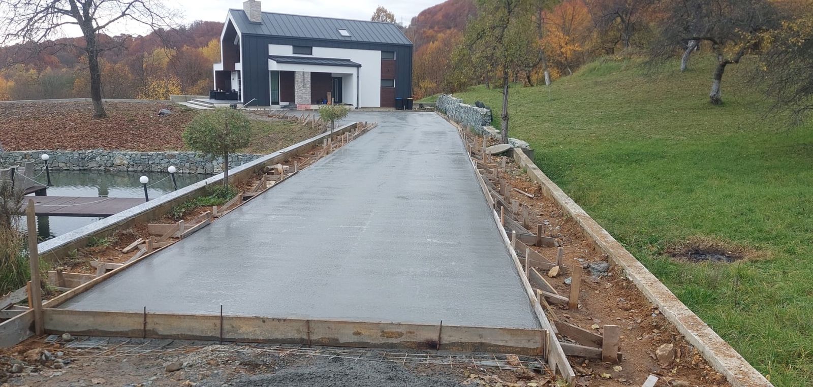 Alee de beton nou turnată la o casă modernă, cu iaz și peisaj de toamnă, Maramureș
