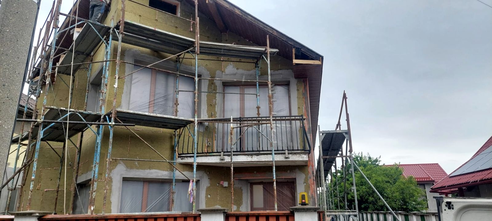 Fațadă în renovare, cu schelă montată și termosistem în lucru