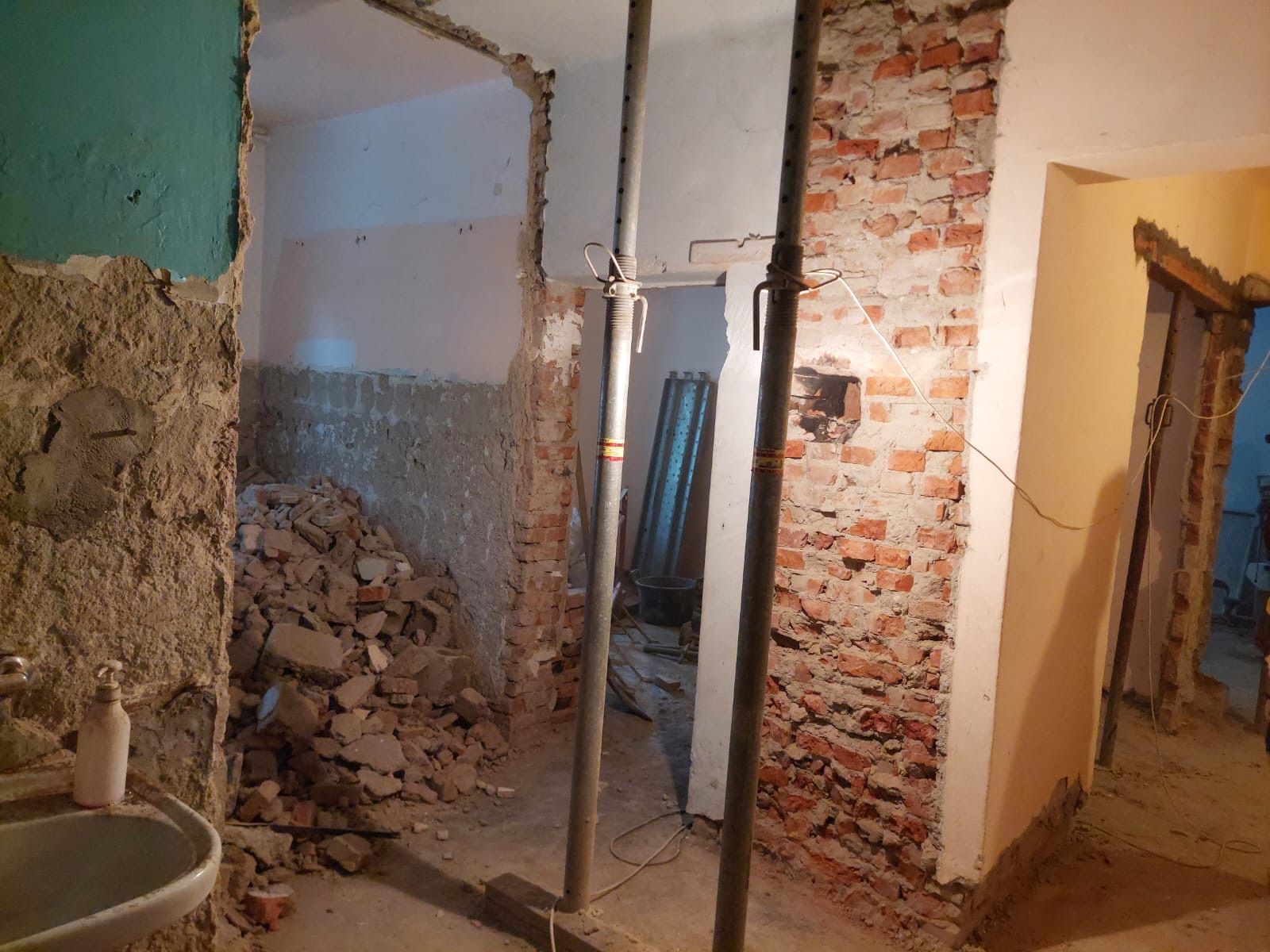 Demolare interioară, cu zid de cărămidă expus și moloz pe jos