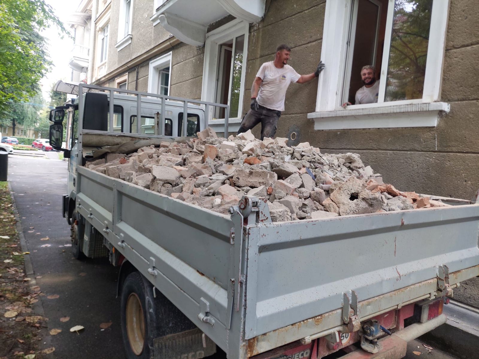 Fațadă în renovare, cu autoutilitară încărcată cu moloz